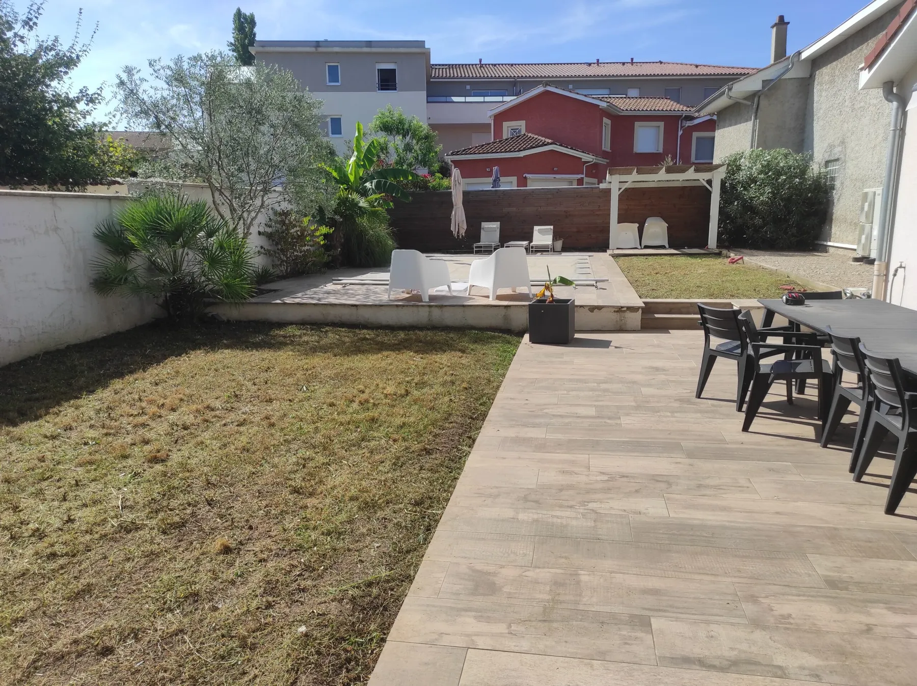 Grande terrasse en dallage grand format avec mobilier de jardin, pelouse en cours de reprise
