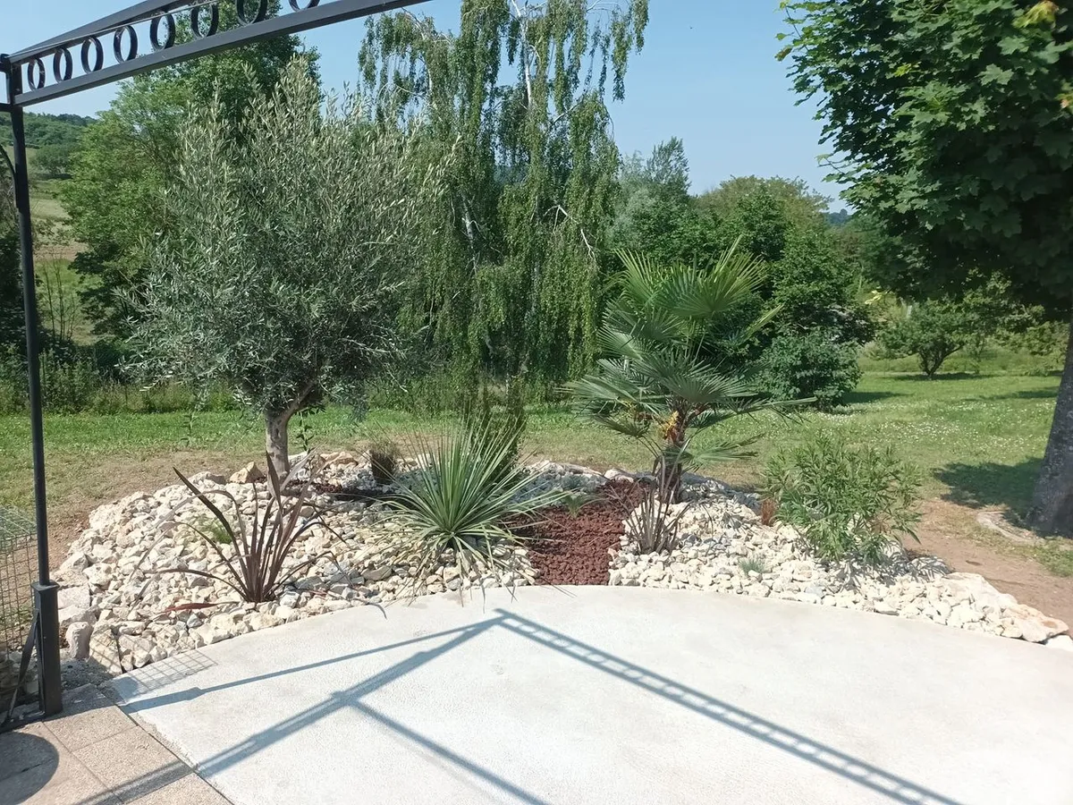 Massif de galets blancs planté de yuccas et d'oliviers en bordure d'une terrasse