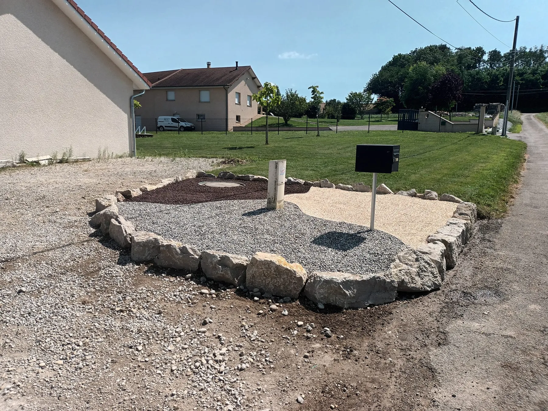 Massif circulaire en gravier ceinturé de blocs de pierre en enrochement